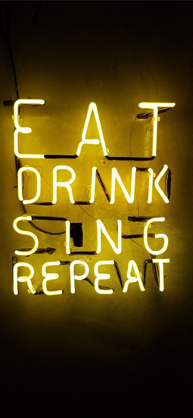 turned on eat drink sing repeat neon signage on wa... iPhone 12 wallpaper 