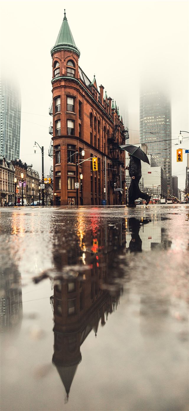 man using umbrella crossing the street during dayt... iPhone 12 wallpaper 