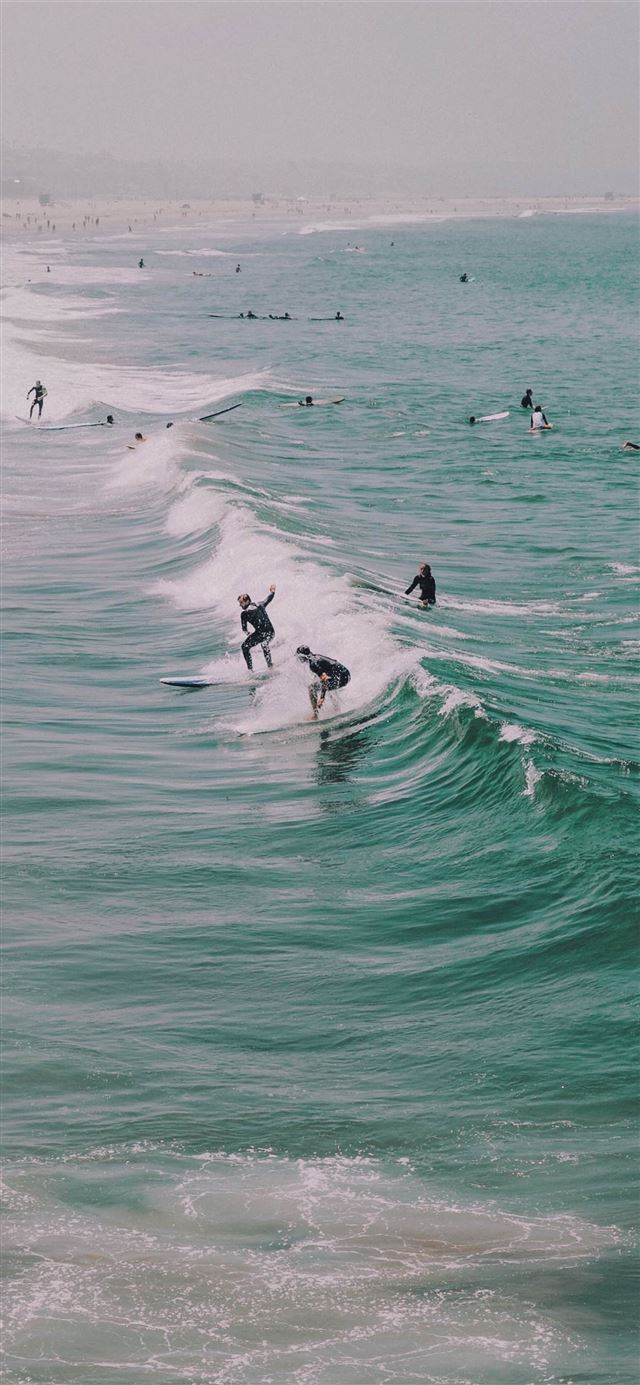 people surfing on ocean waves iPhone 12 wallpaper 