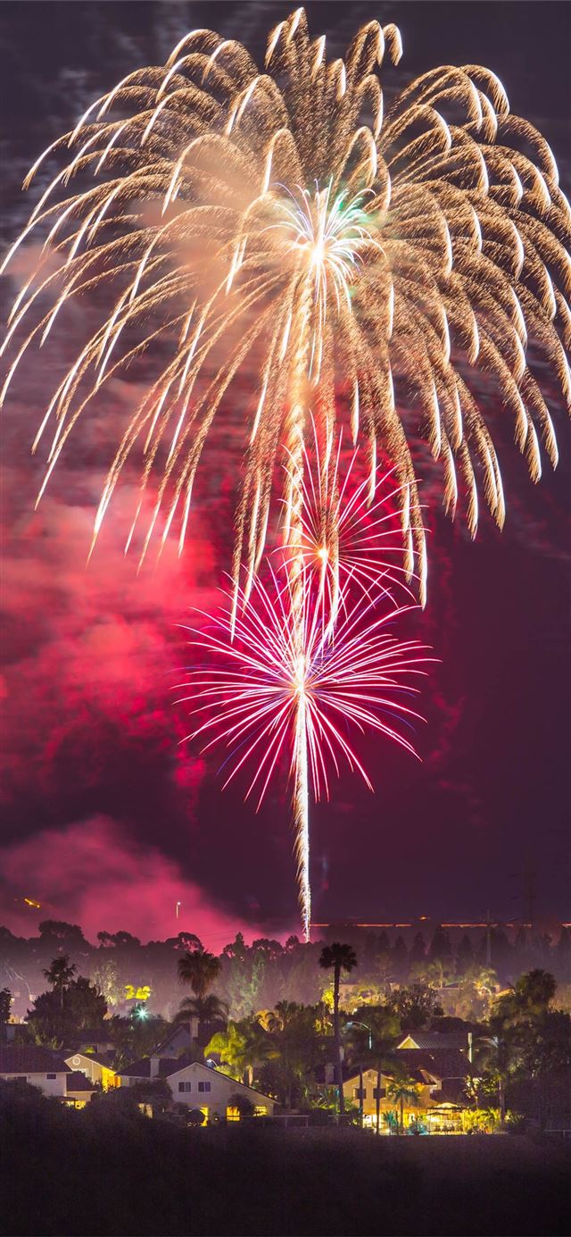 fireworks above houses at night time iPhone 12 wallpaper 