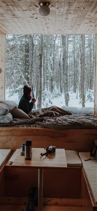 woman sitting on bed watching by the window during... wallpaper