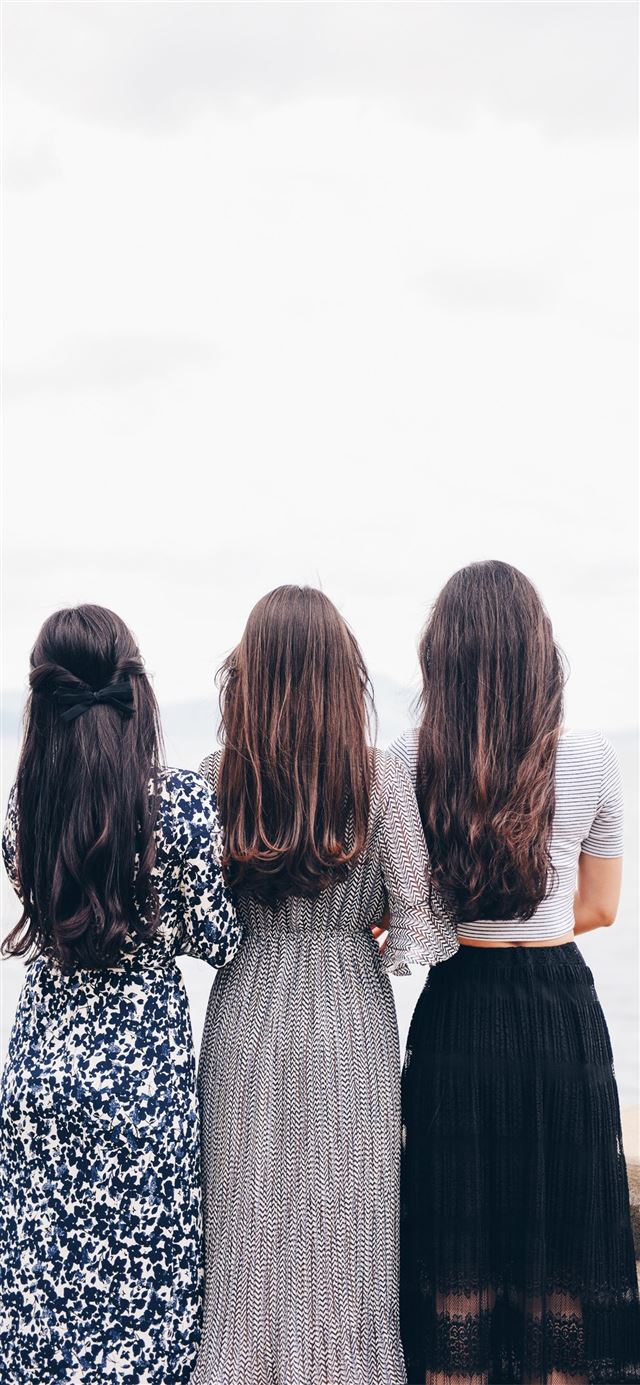 three woman looking back and facing body of water iPhone 12 wallpaper 