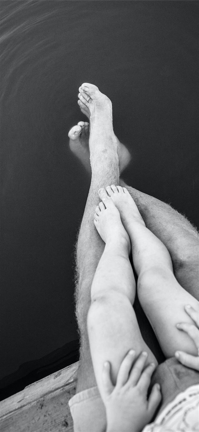 grayscale photo of person's feet on body of water iPhone 12 wallpaper 