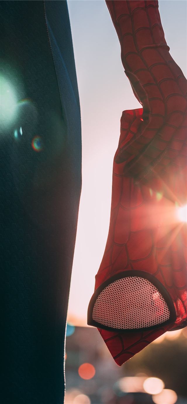 person holding Spider Man mask iPhone 12 wallpaper 
