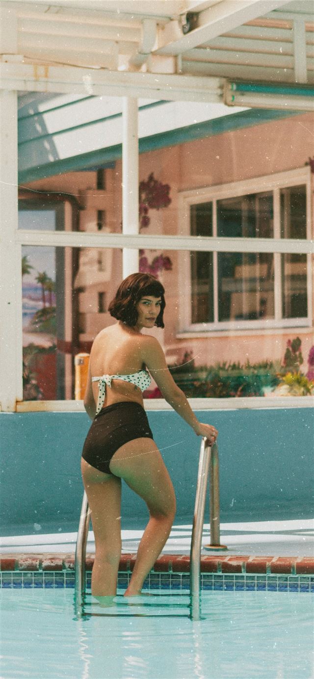 woman standing on pool ladder at daytime iPhone 12 wallpaper 