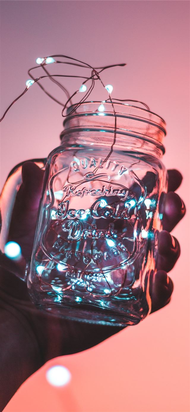 person holding clear glass mason jar with strip li... iPhone 12 wallpaper 