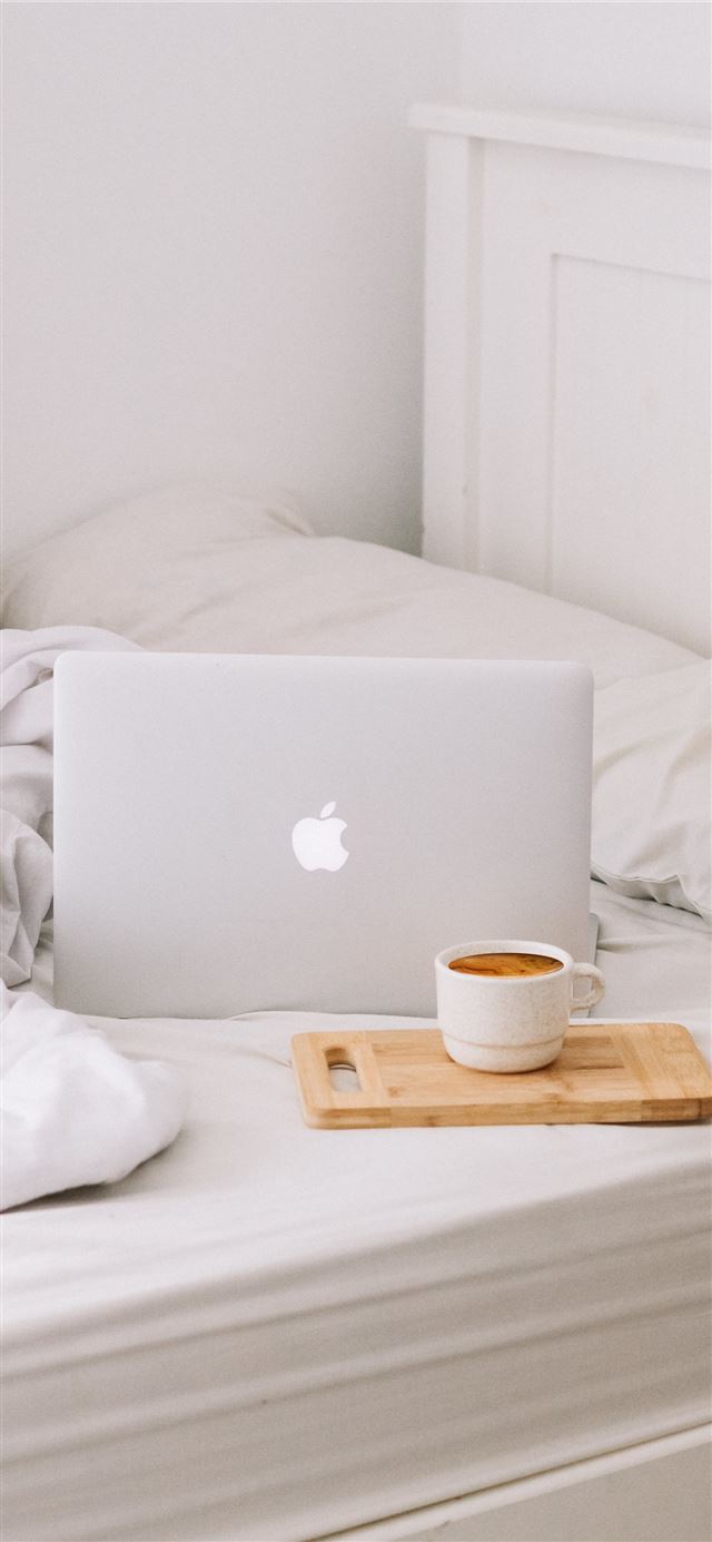 MacBook beside teacup with latte iPhone 12 wallpaper 