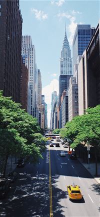 yellow car running on the street between the build... wallpaper