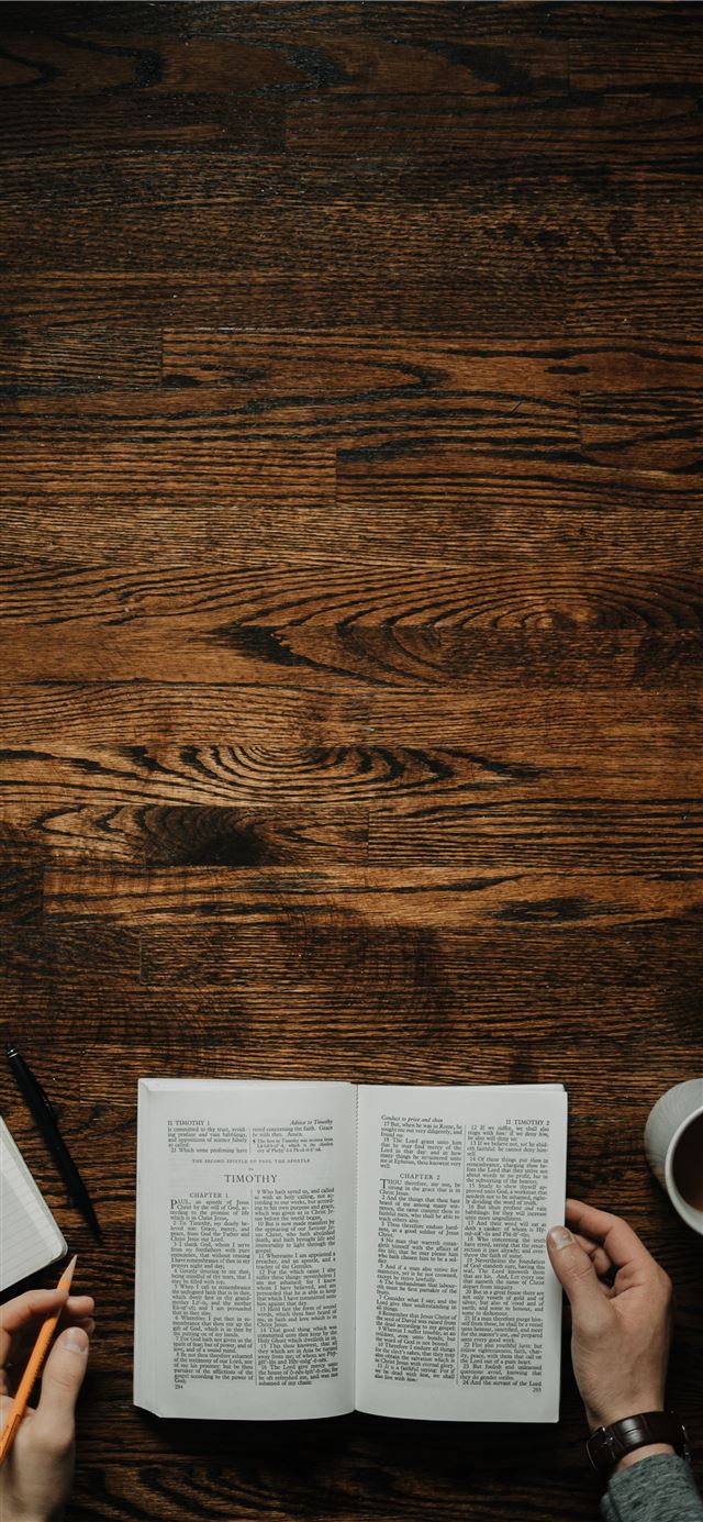 person sitting by the table opening book iPhone 12 wallpaper 