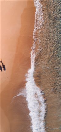 aerial photography of two persons walking along se... iPhone 12 wallpaper