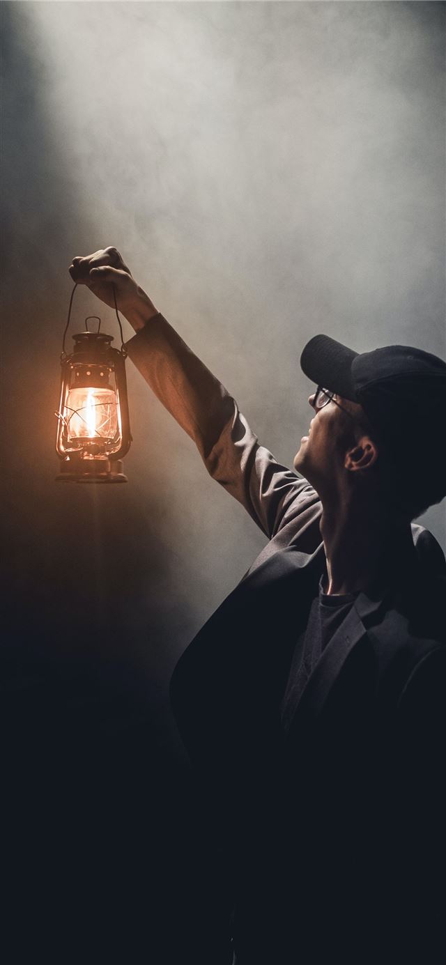 man holding lighted gas lantern iPhone 12 wallpaper 