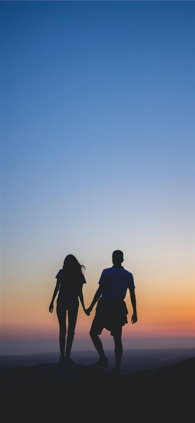 man and woman holding hands in silhouette photogra... iPhone 12 wallpaper 