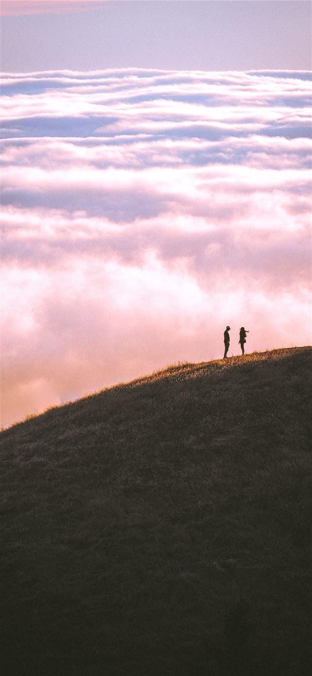 couple standing on grass field mountain iPhone 12 wallpaper 