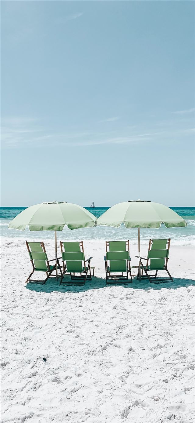 green chairs under umbrellas on shore iPhone 12 wallpaper 