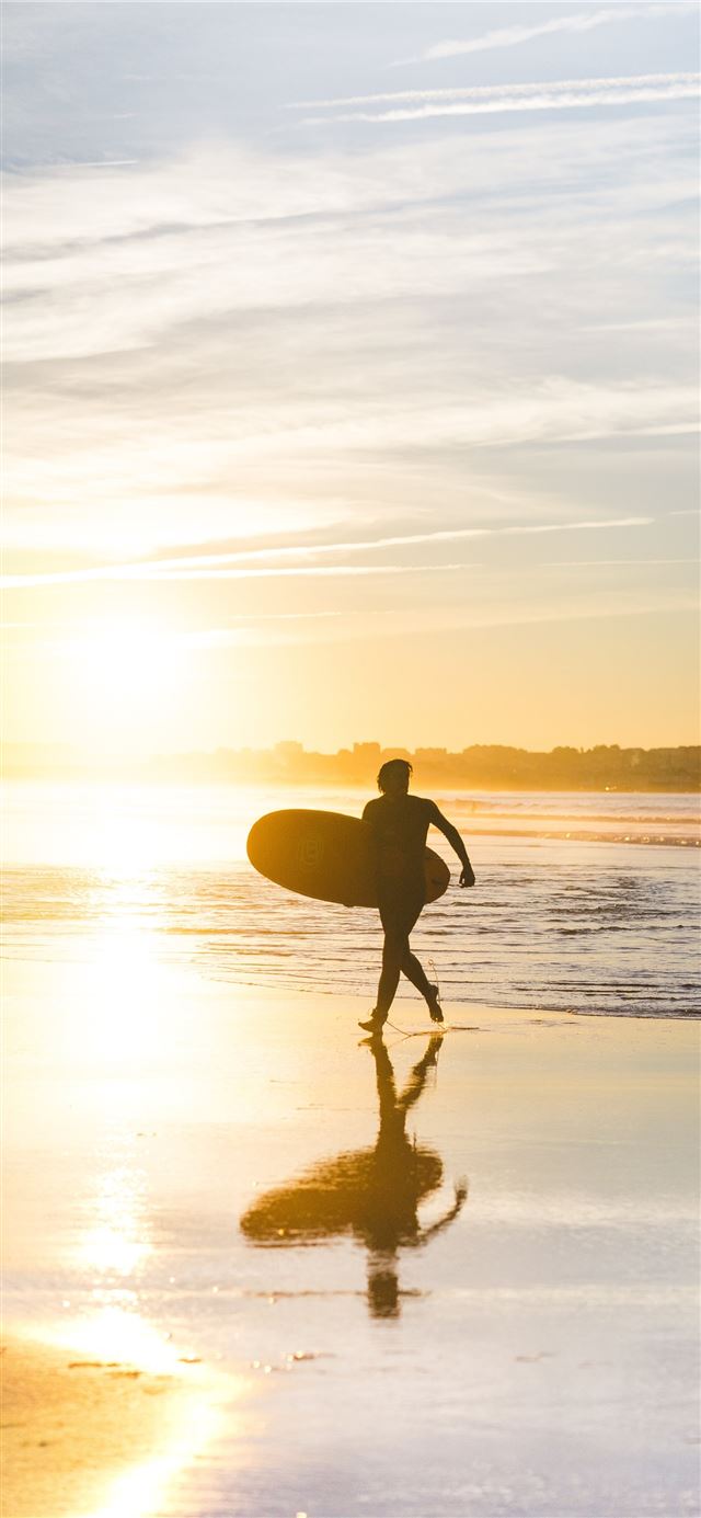 man holding surfboard at seaside iPhone 12 wallpaper 