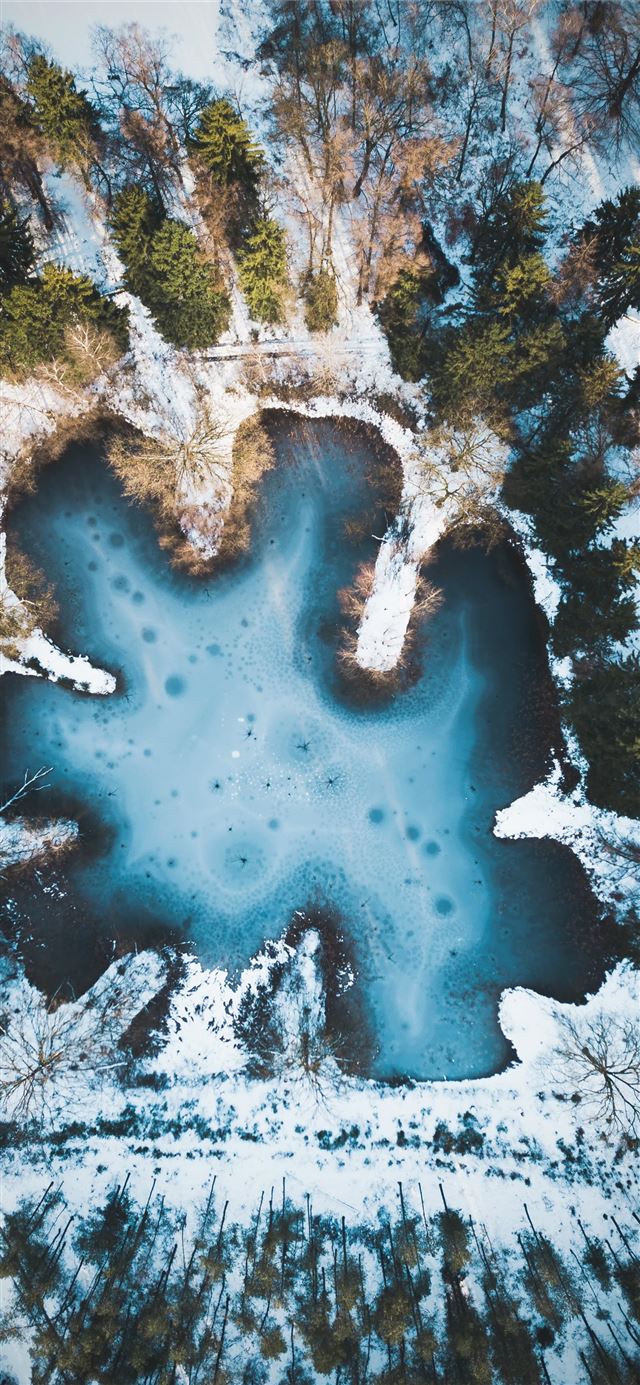 body of water surrounded by snow covered ground wi... iPhone 12 wallpaper 