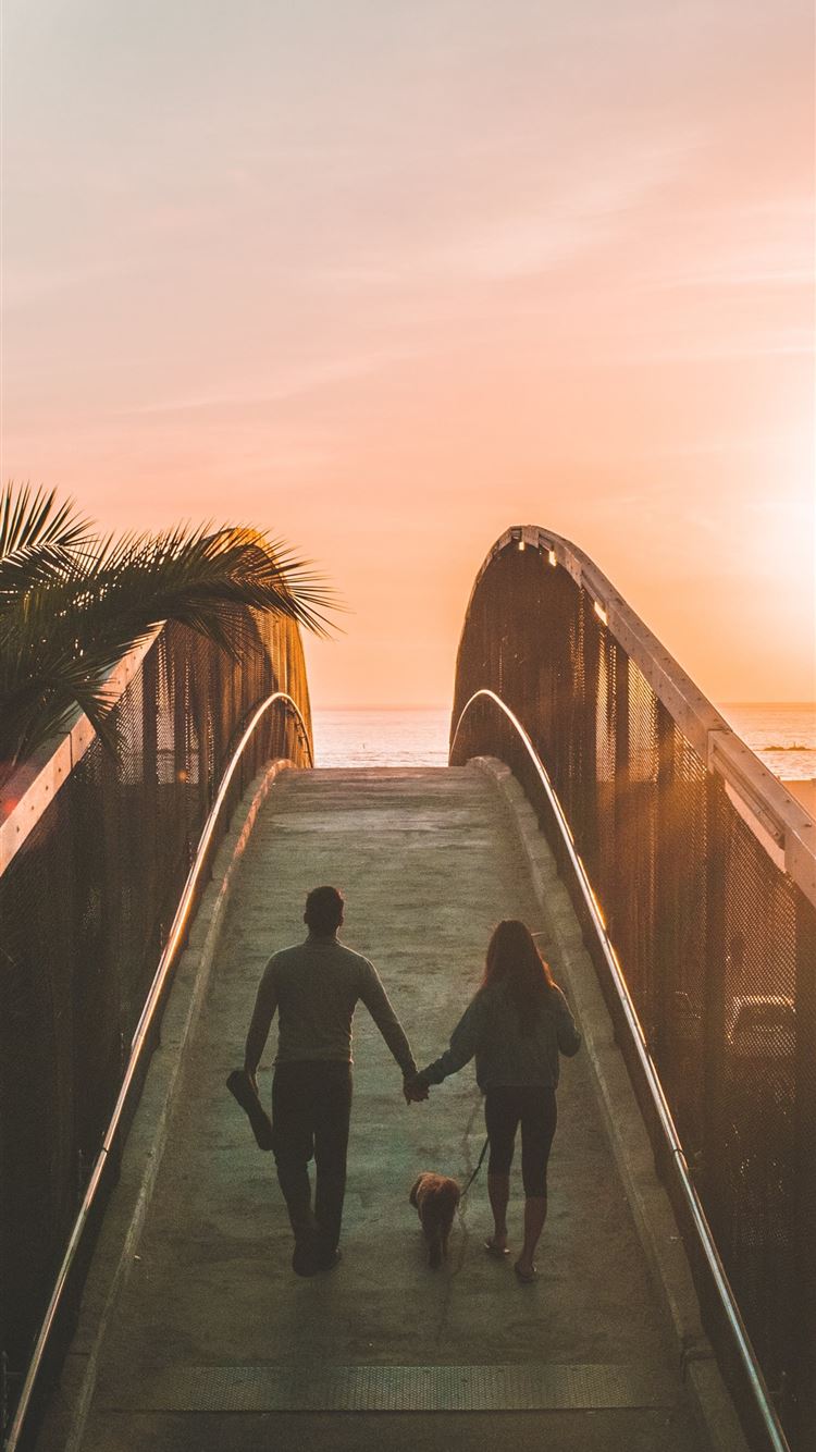 man and woman holding hand while walking on bridge iPhone 8 wallpaper 