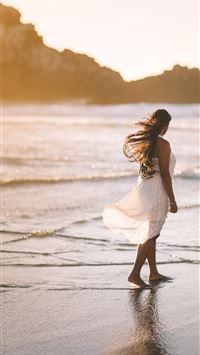 selective focus photo of woman standing on sea sho... wallpaper