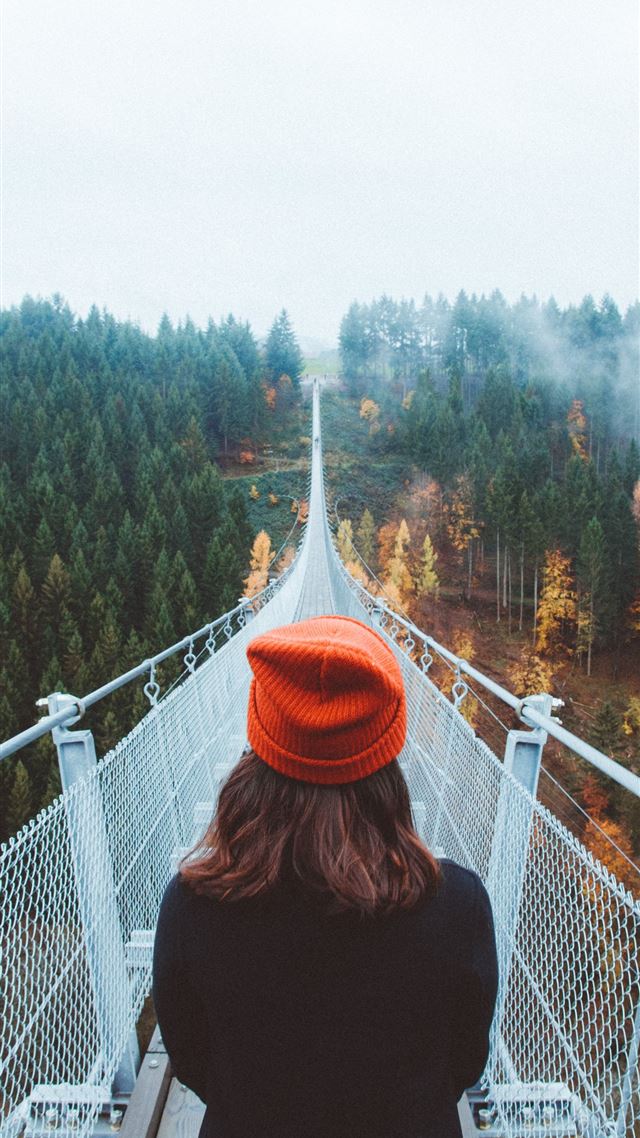 1284x2778 woman wearing knit cap walking on white bridge bet... -  iPhone 8 Wallpaper