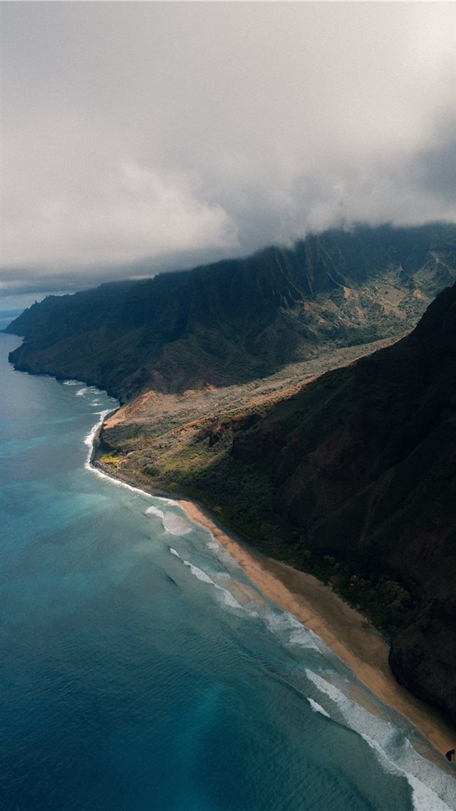 1080x1920 green mountain near body of water under grey sky - ocean iPhone 8 Wallpaper