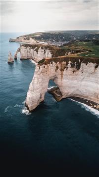 brown and green cliff and body of water wallpaper
