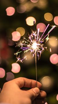 bokeh photography of person holding fireworks wallpaper