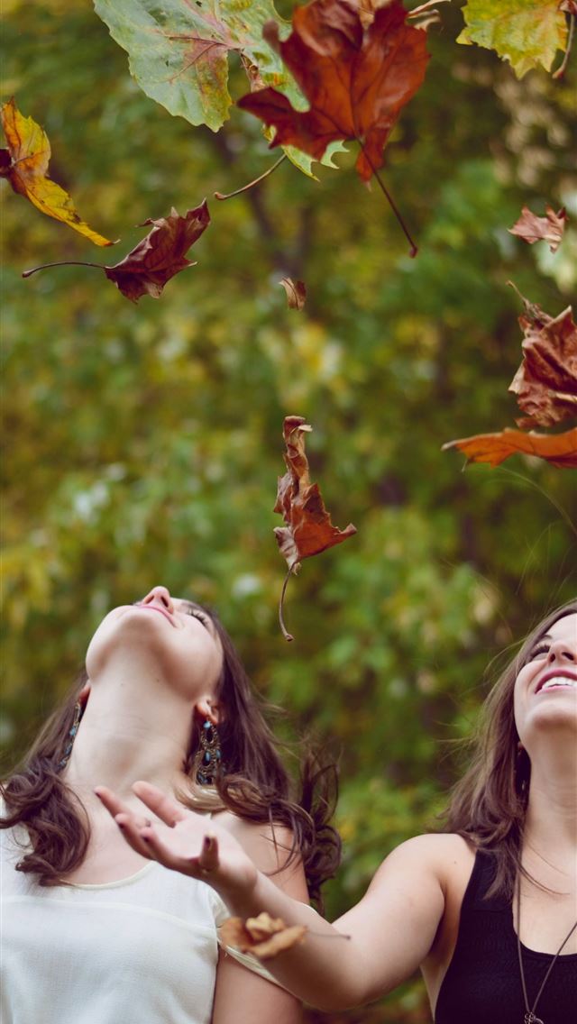 640x1136 photo of two women throwing leaves during daytime - indiana iPhone Wallpaper
