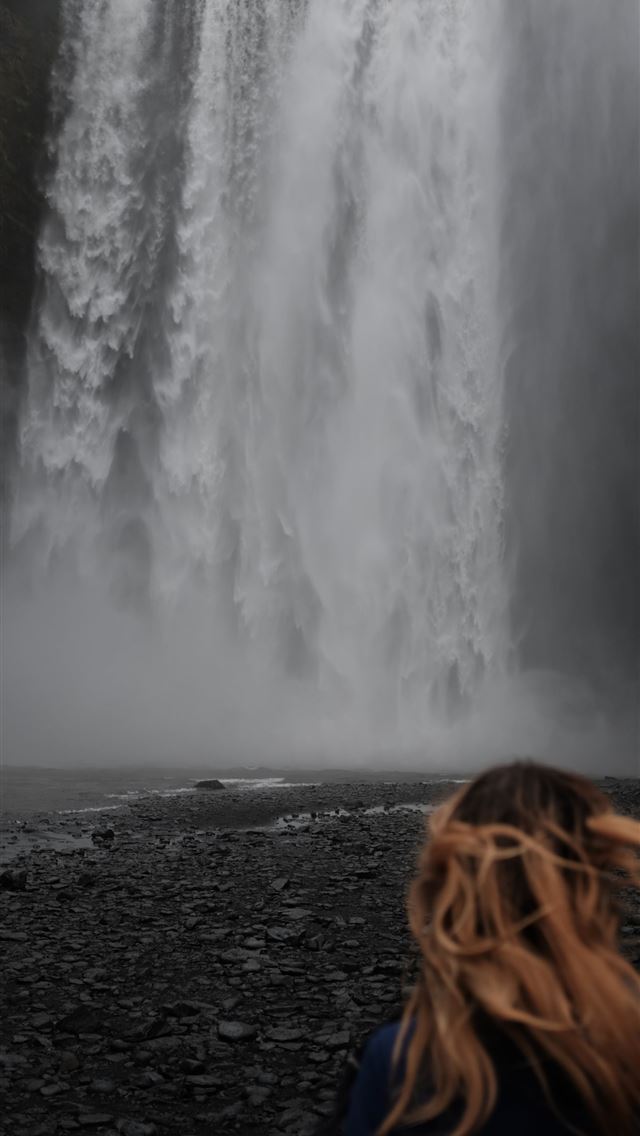 640x1136 woman standing near waterfalls - iceland iPhone Wallpaper
