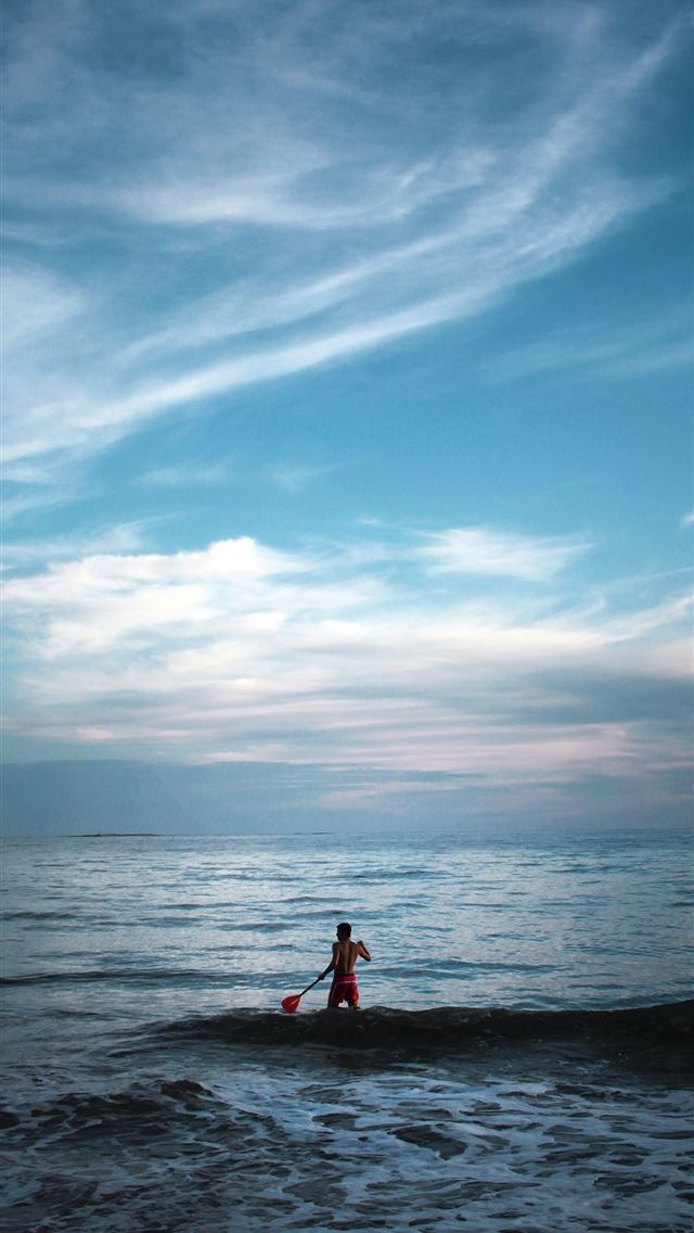 640x1136 man standing on body of water holding paddle - beach iPhone Wallpaper