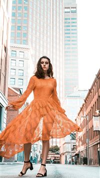 woman in orange long sleeved dress between buildin... wallpaper