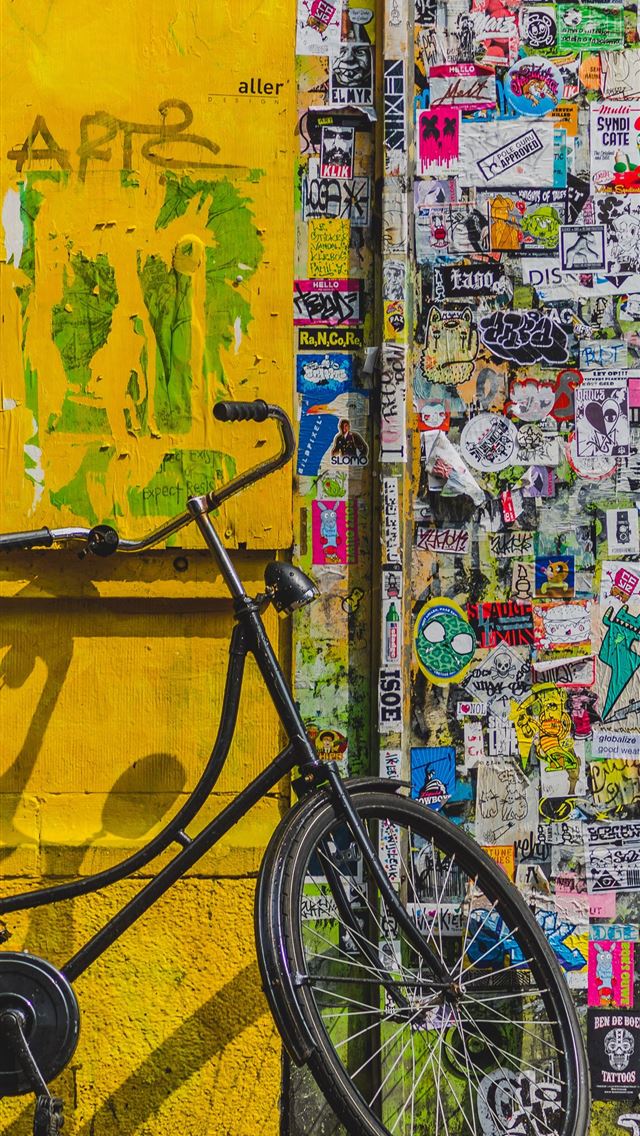 640x1136 bike parked beside wall full of stickers - yellow iPhone Wallpaper