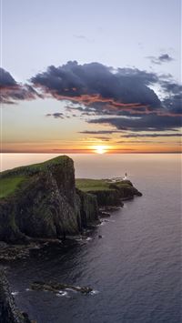 green and black mountain beside sea during sunset wallpaper