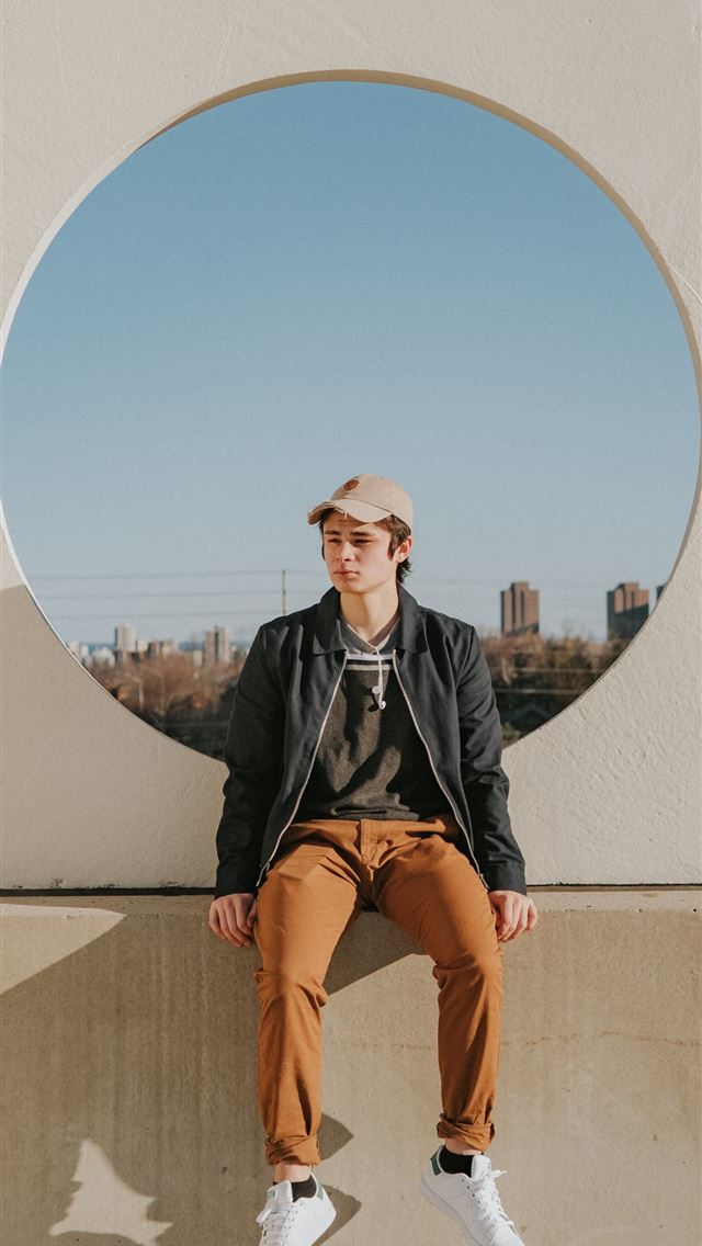 640x1136 man sitting on gray concrete wall - circle iPhone Wallpaper