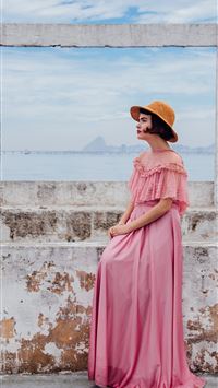 woman wearing pink dress standing next to white wa... wallpaper