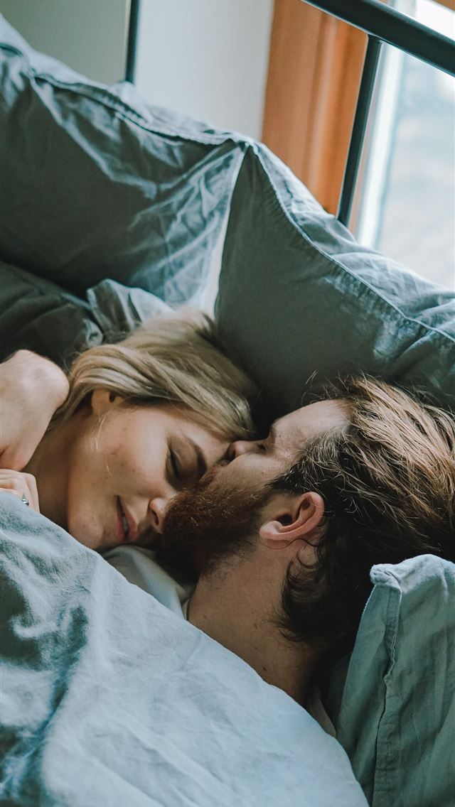 640x1136 man kissing woman's forehead while lying on bed - united kingdom iPhone Wallpaper