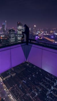 man standing on building rooftop during nigh time wallpaper