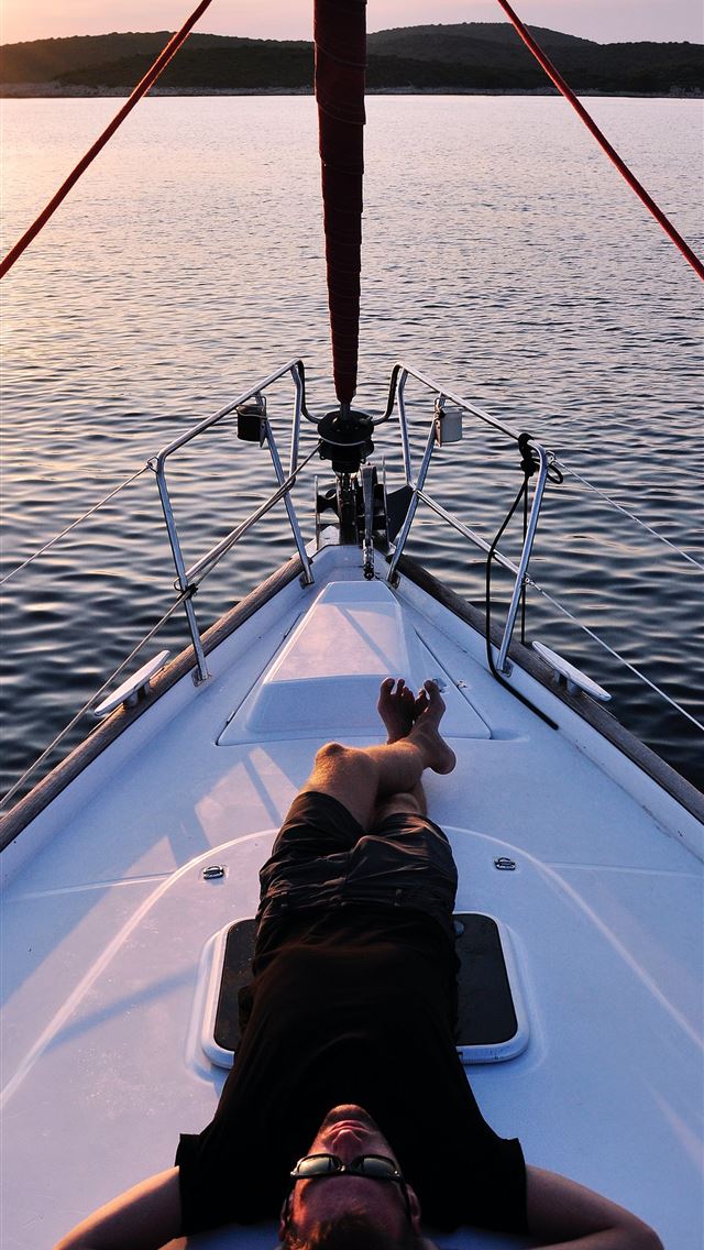1284x2778 man lying on white boat - croatia iPhone Wallpaper