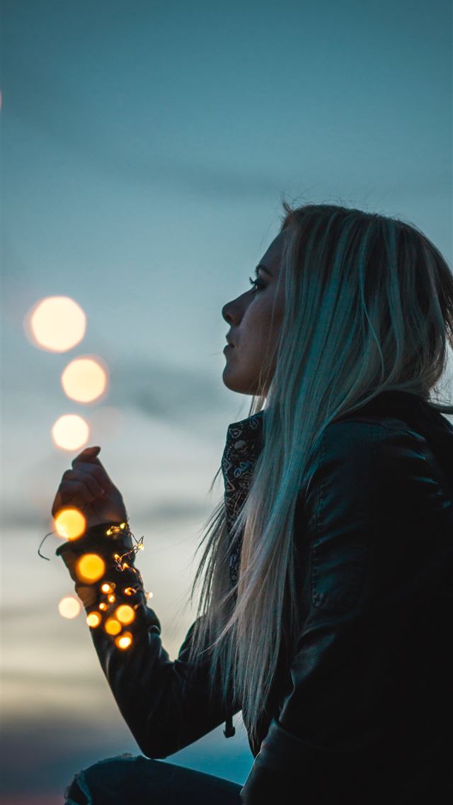 1284x2778 woman sitting holding string lights - bokeh iPhone Wallpaper