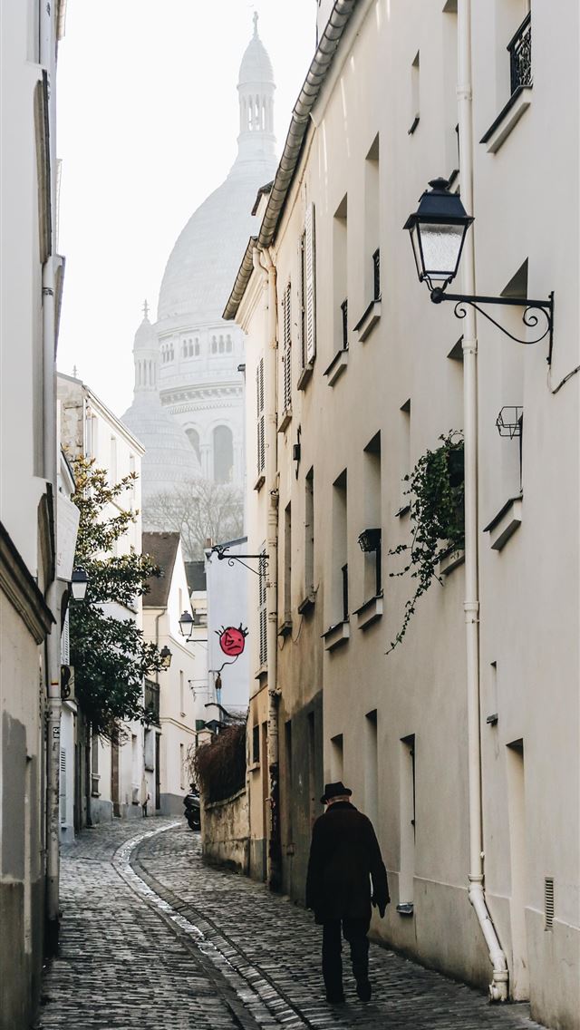 1284x2778 man walking near concrete building - france iPhone Wallpaper