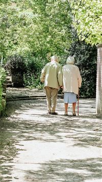 man and woman walking on road during daytime wallpaper