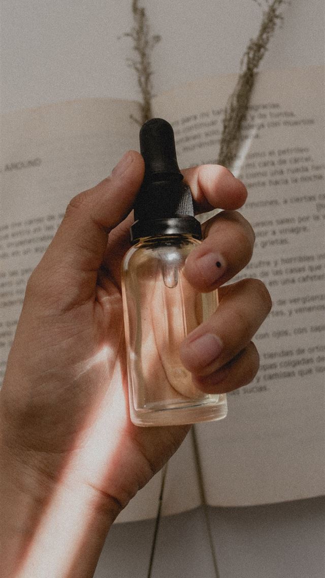 1284x2778 person holding small clear drop bottle - aesthetic iPhone Wallpaper