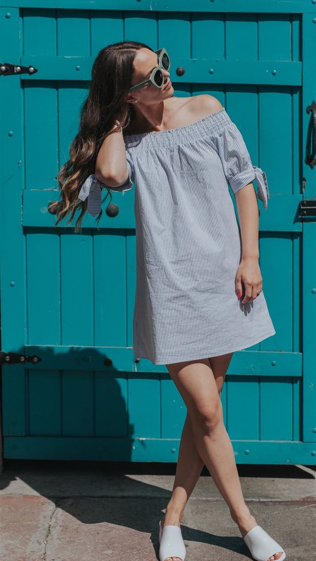 1284x2778 woman touching her hair standing near teal gate -  iphone 13 Wallpaper
