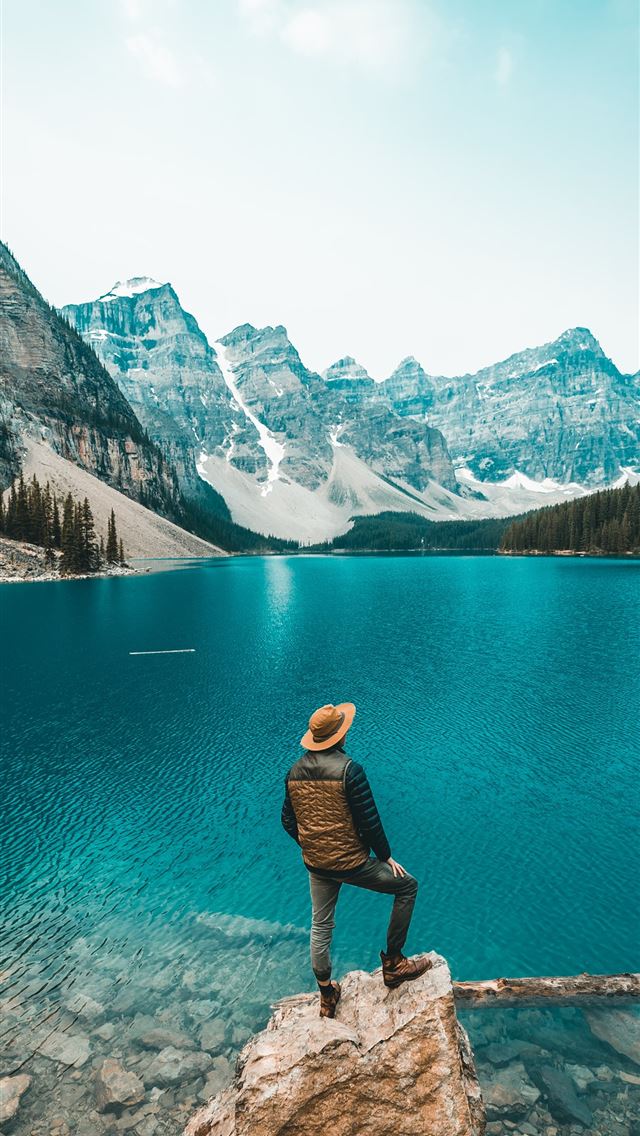 1284x2778 man standing on rock near lake - moraine lake iPhone Wallpaper