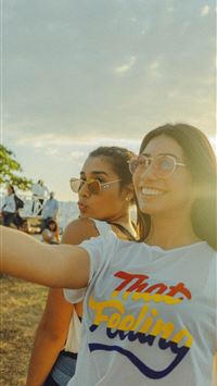 women taking photo near beach at daytime wallpaper
