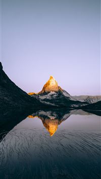 mountain and body of water under white clouds duri... wallpaper