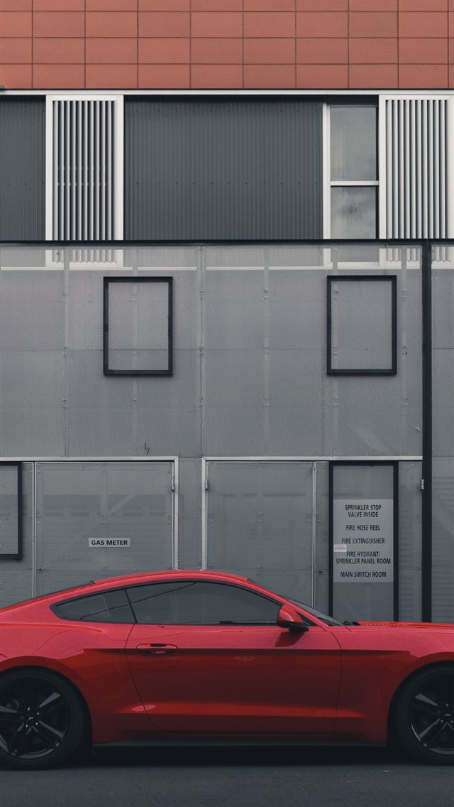1284x2778 red Ford Mustang coupe parked beside the building - modern iPhone Wallpaper
