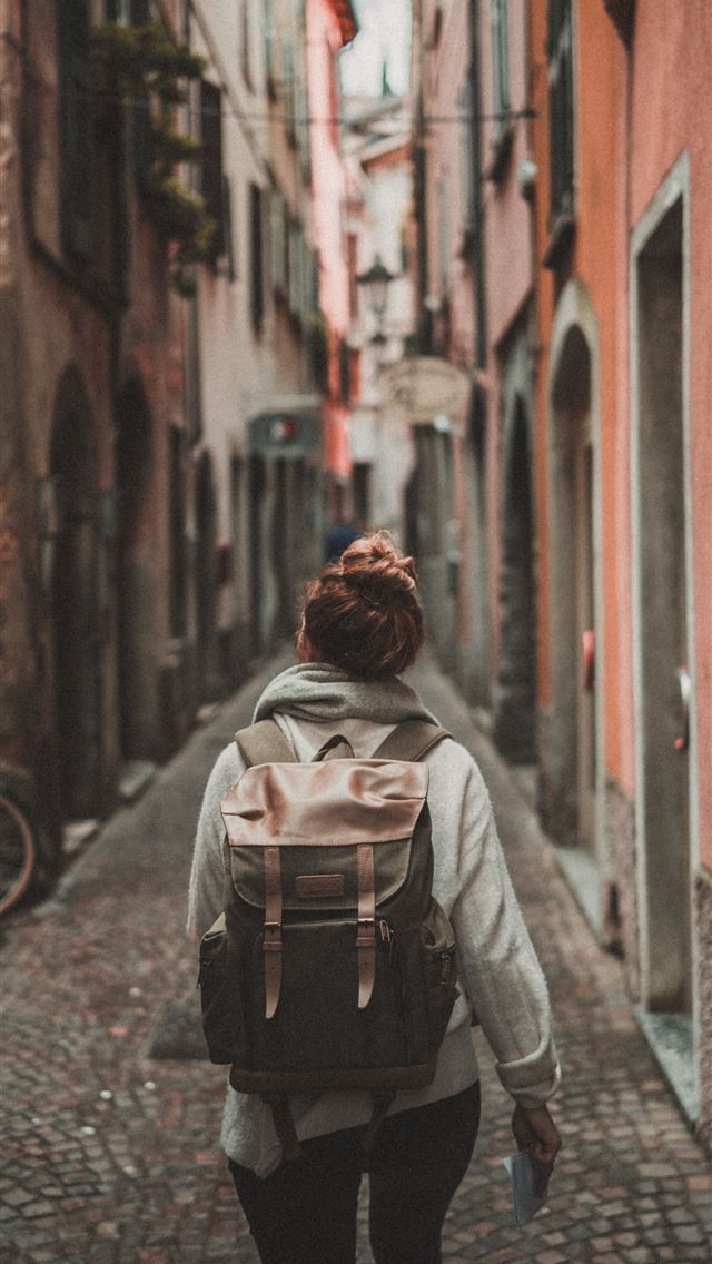 1284x2778 woman walking on street surrounded by buildings - italy iPhone Wallpaper