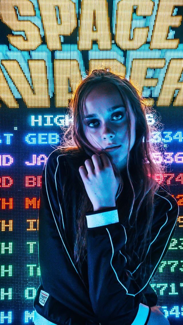 1284x2778 woman posing for photo in front of Space Invaders ... - neon iPhone Wallpaper