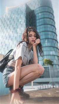 woman in blue denim jacket sitting on red metal po... wallpaper