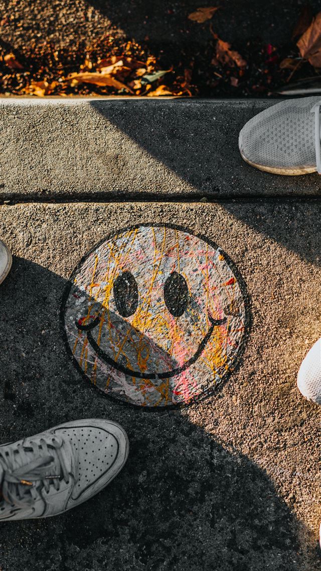 1284x2778 smiley paint on gray ground in front of people - graffiti iPhone Wallpaper